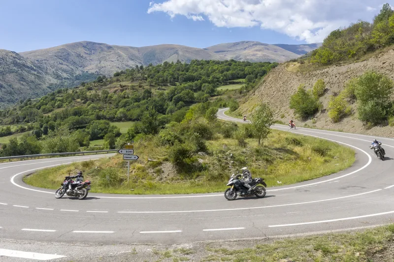 Two motorcyclists following a sweeping bend through the Spanish mountain landscape